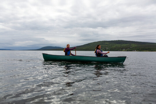 Female friends rowing boat in river against sky