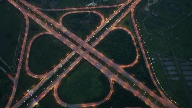 High altitude drone video image of glowing cloverleaf style highway interchange at blue hour in Dong Anh District Hanoi.