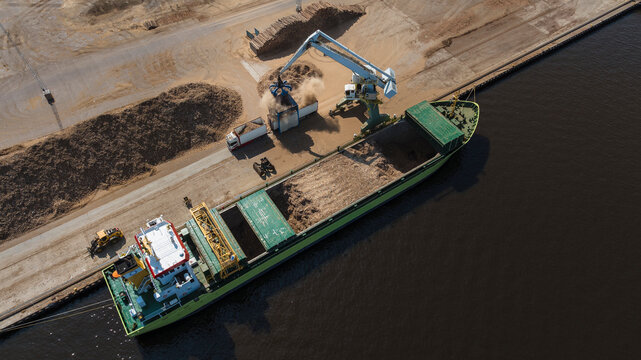 High angle view of machine unloading sand from ship at harbor