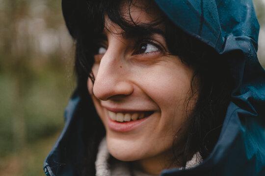 Close-up of smiling woman wearing raincoat looking away