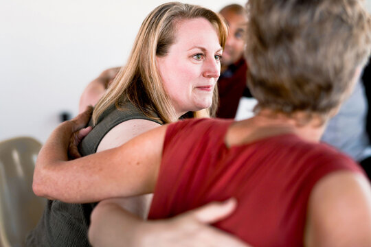 Two women embracing in a warm, supportive setting.