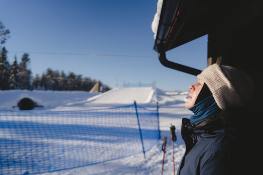 Woman in warm clothes sunbathing outside cabin