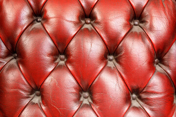 Naklejka premium Detailed view of deep red leather upholstery with classic diamond tufting pattern.