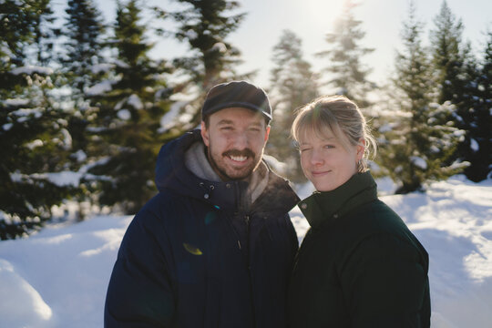 Smiling woman winking while standing next to man during winter season