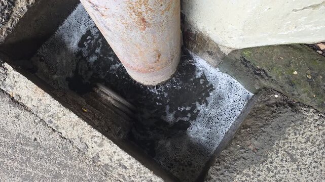 Polluted drain overflowing with bubbling dirty stagnant water, showing environmental hazard and urban infrastructure issues from a blocked sewage pipe