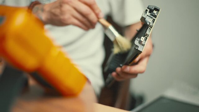 Man repairs graphics card in home workshop with tools on desk