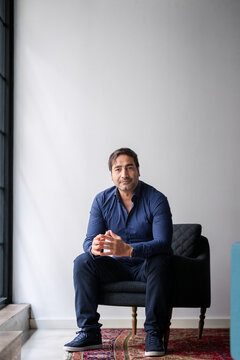 Portrait of mature businessman sitting on armchair against wall in new office