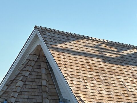 Natural cedar shake rooftop with wooden shingles showing residential exterior roofing maintenance concept