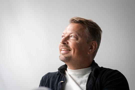 Smiling mature businessman looking away against wall