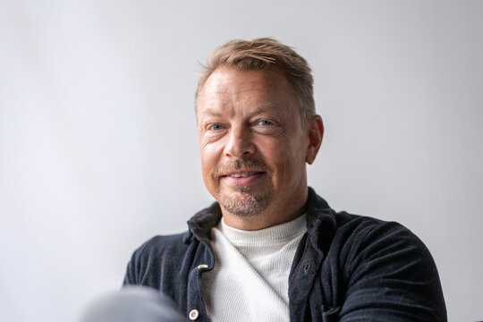 Portrait of mature male business expert sitting against wall in office