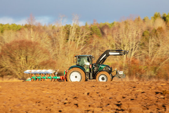 Modern tractor pulling multi-furrow plough through field