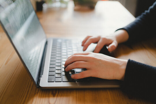 Hand of female freelancer typing on laptop while working from home