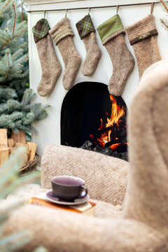 Five neutral-toned knit Christmas stockings hanging on mantelpiece above fireplace in backyard