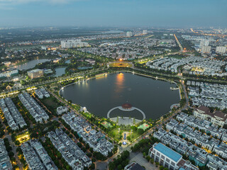 Obraz premium Twilight aerial panorama of a brightly illuminated lake bordered by villas and urban streets in Long Bien district, Hanoi.