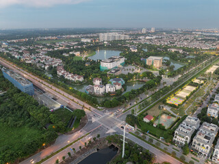Fototapeta premium Evening aerial photograph of a green urban enclave with villas, roads, and illuminated intersections in Long Bien, Hanoi.