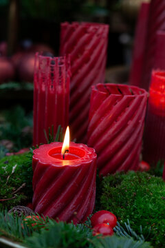 Igniting red candle kept on spruce tree leaves