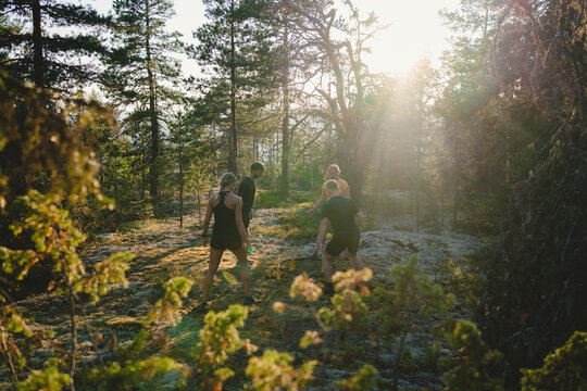 Male and female friends playing spikeball in forest at sunny day
