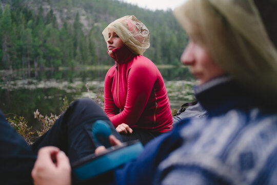 Young woman sitting with friend near lake