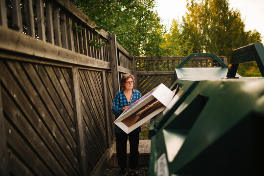 Woman throwing cardboard box in garbage bin