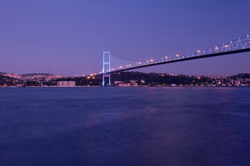 Obraz premium Beautiful night view of the Bosphorus Bridge illuminated at blue hour in Istanbul, Turkey. Long exposure shot of the suspension bridge connecting Europe and Asia, scenic twilight cityscape, Beylerbeyi