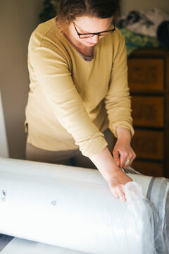 High angle view of woman removing plastic cover of duvet