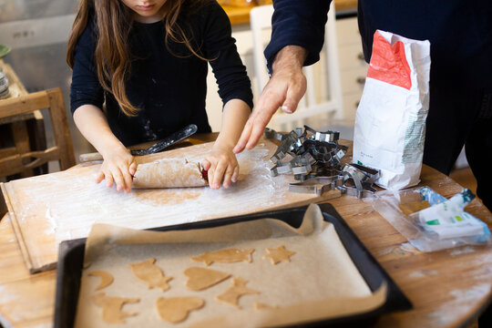 Girl rolling gingerbread dough for cookies at home