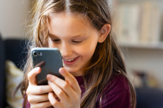 Happy girl using smart phone at home