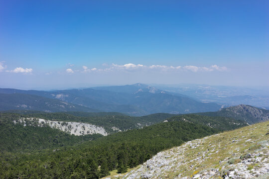 Panoramic scenic view of Mount Ida (Kaz Daglari) national park with green pine forests, rocky slopes, and misty mountain ranges under a clear blue sky. Nature tourism, hiking, and travel  in Canakkale
