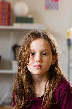 Portrait of long haired girl with blank expression at home