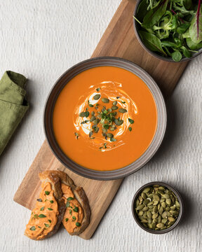 Directly above view of creamy pumpkin soup garnished with seeds and cream