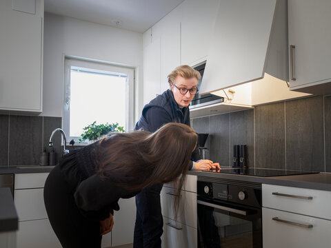 Male technician explaining chimney problem to homeowner while standing in kitchen