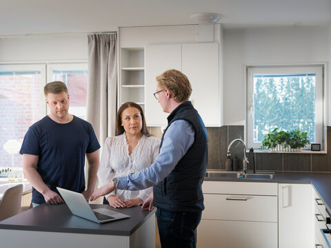 Male architect explaining home improvement plan to couple on laptop