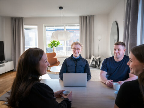Smiling male building contractor using laptop while sitting with family at table in home