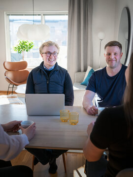 Smiling male architect wearing eyeglasses talking with people at home