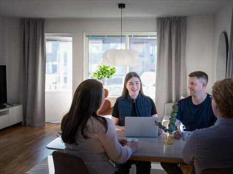 Smiling female building contractor using laptop while sitting with family at table in home