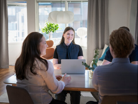 Smiling female agent using laptop while sitting with family at table in home