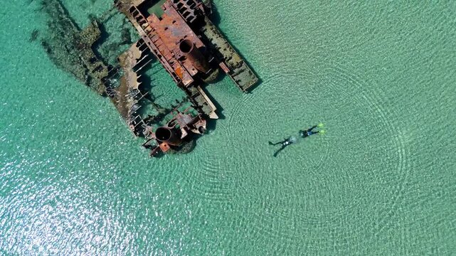 Aerial view of the famous Epanomi shipwreck submerged in crystal clear turquoise waters near the sandy beach spit in Halkidiki, Greece.