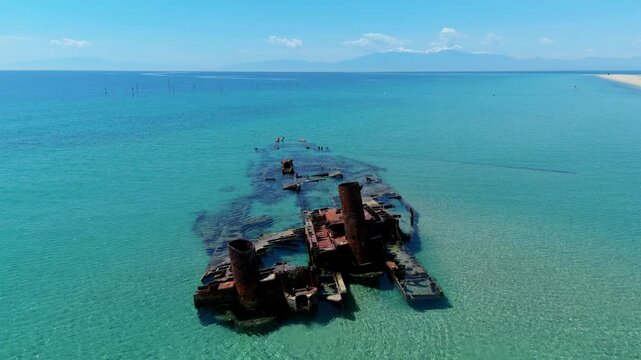 High angle aerial drone view of the historic rusty Epanomi shipwreck submerged in crystal clear turquoise blue sea water near the beach in Greece
