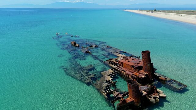 High angle aerial drone view of the historic rusty Epanomi shipwreck submerged in crystal clear turquoise blue sea water near the beach in Greece