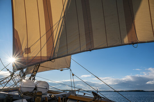 Scenic view of sailing ship on sea at sunny day against cloudy sky