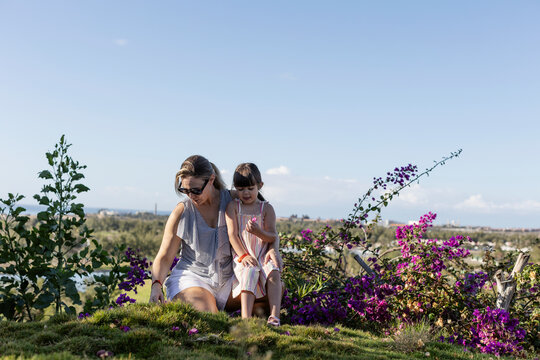 Mother and daughter spending leisure time in garden against sky at sunny day