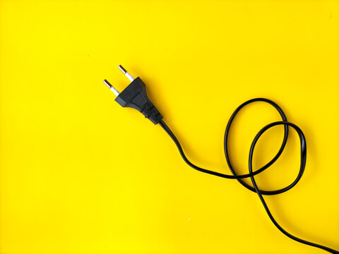 European two-pin power cord on bright yellow background. Concept of electricity, energy, technology, connection, and power supply.