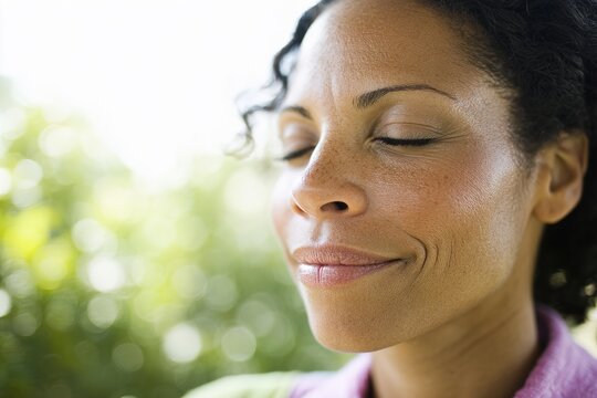Young woman with closed eyes smiling softly in natural outdoor light