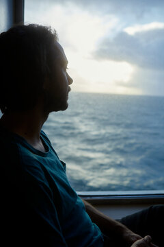Carefree man looking at sea view through window while traveling in ferry