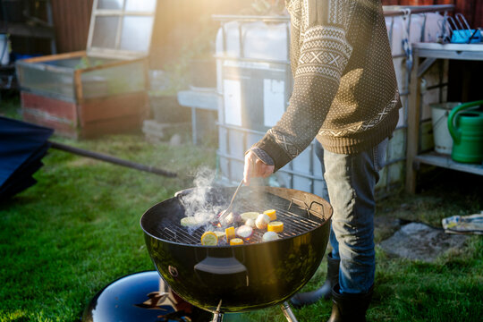 Senior man grilling vegetables on barbecue in back yard