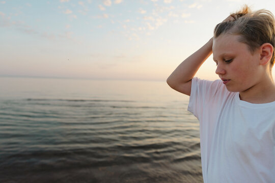 Boy with hand in hair spending leisure time near sea at beach