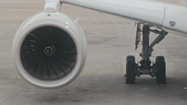 Close up view of a commercial jet engine and wing parked on the airport tarmac under bright daylight