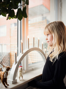 Cute blond girl looking out through window in home