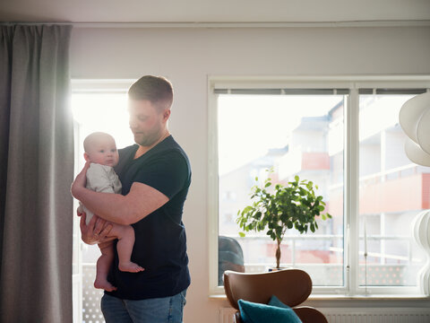 Father embracing baby son while spending leisure time at home
