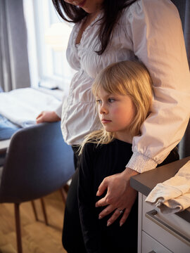 Blond girl standing with mother in home